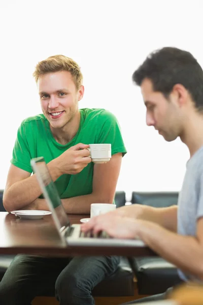 Estudiantes usando laptop mientras toman café en la cafetería —  Fotos de Stock