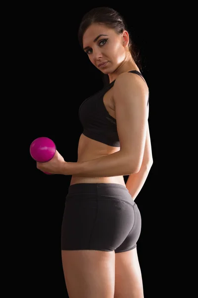 Portrait of beautiful fit woman lifting a pink dumbbell — Stock fotografie