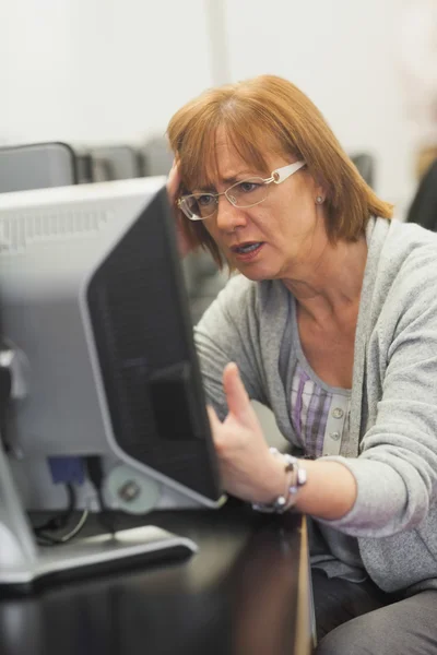 Irritated mature student working on computer