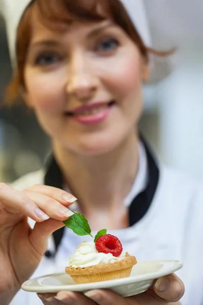 Jolie chef mettant de la feuille de menthe sur un petit gâteau sur assiette — Photo