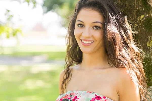 Stylish cheerful brunette leaning against tree — Stock Photo, Image