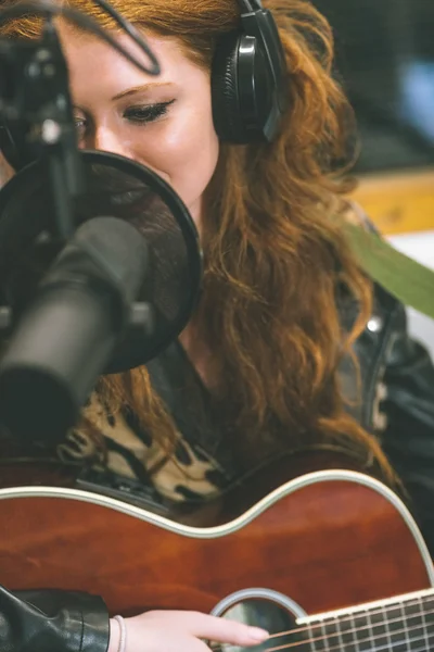Obsah krásná zpěvačka nahrávání a hraní na kytaru — Stock fotografie