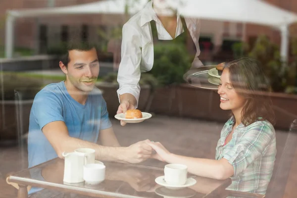 A couple holding hands while waitress serving food — Stock Photo, Image