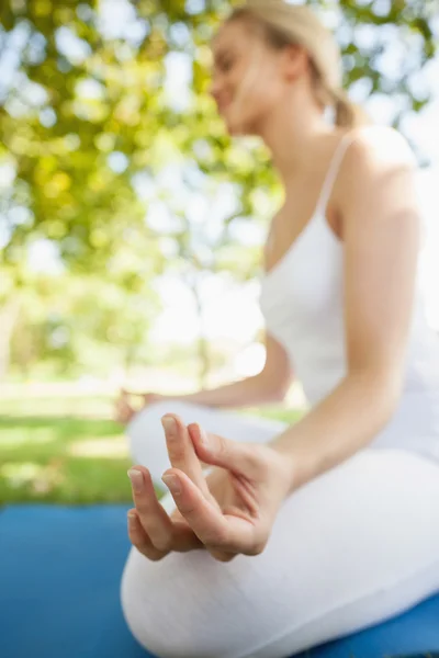 Mujer joven y pacífica sentada en un mapa de ejercicios meditando — Foto de Stock