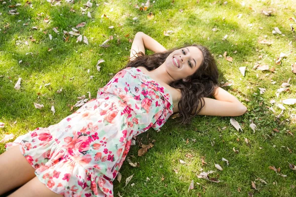 Elegante sorrindo morena deitada na grama — Fotografia de Stock