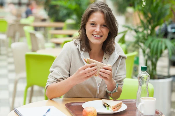 Vrouwelijke student boterham eten in de cafetaria — Stockfoto