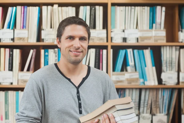 Olgun öğrenci ayakta tutan bazı kitaplar kitaplığa — Stok fotoğraf