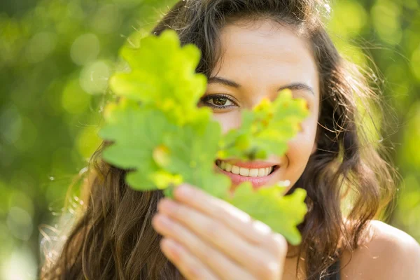 Wunderschöne fröhliche Brünette hält ein Blatt — Stockfoto