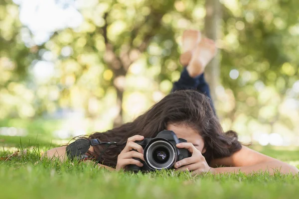 Jonge vrouw met behulp van haar camera voor het nemen van een foto liggend op een wet — Stockfoto