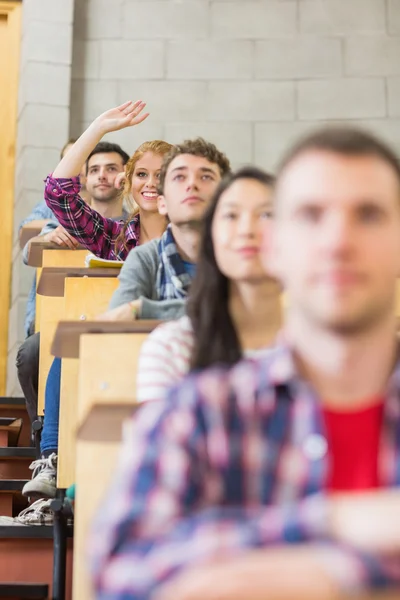 Lachende vrouwelijke student verhogen hand in klaslokaal — Stockfoto