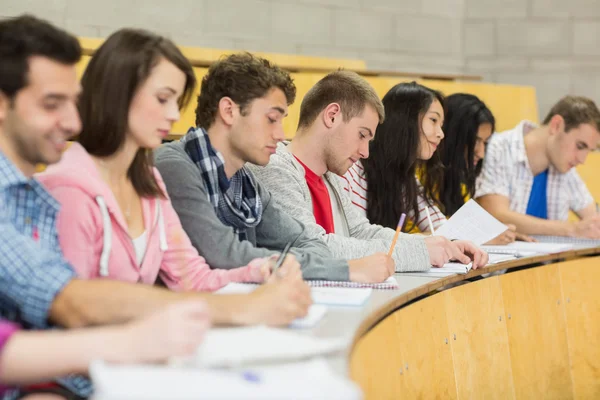 Estudiantes escribiendo notas seguidas en la sala de conferencias —  Fotos de Stock