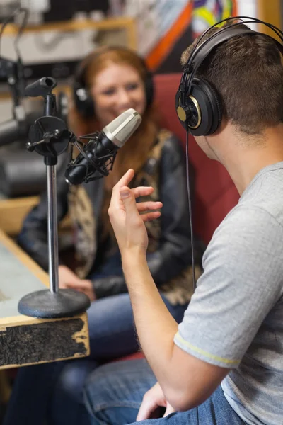 Привлекательный улыбающийся радиоведущий берёт интервью у гостя — стоковое фото