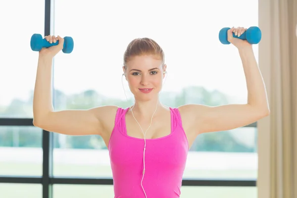 Fit woman exercising with dumbbells in fitness studio — Stock Photo, Image