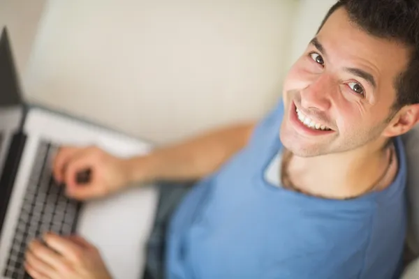 Vista de ángulo alto del hombre alegre casual usando el ordenador portátil —  Fotos de Stock