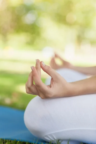 Seção média de mulher jovem meditando sentado em um tapete de exercício — Fotografia de Stock