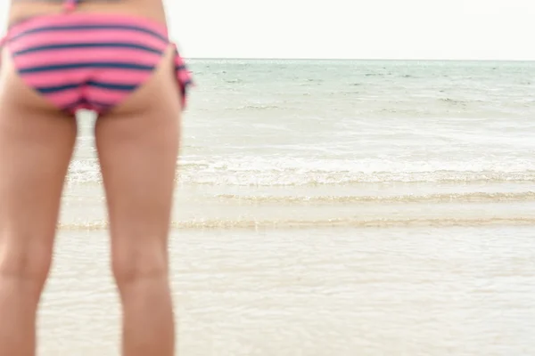 Orta bölümde plaj altındaki çizgili bikini içinde bir kadın — Stok fotoğraf