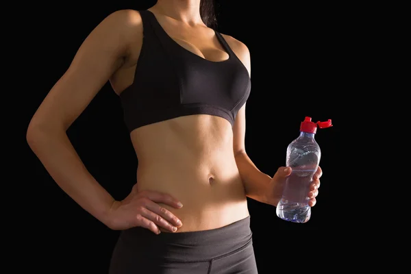 Mid section of slim woman holding a bottle of water — Stock Photo, Image