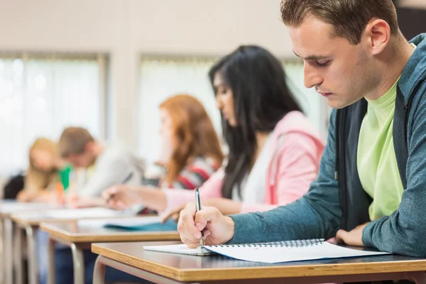 Jóvenes estudiantes escribiendo notas en el aula — Foto de Stock