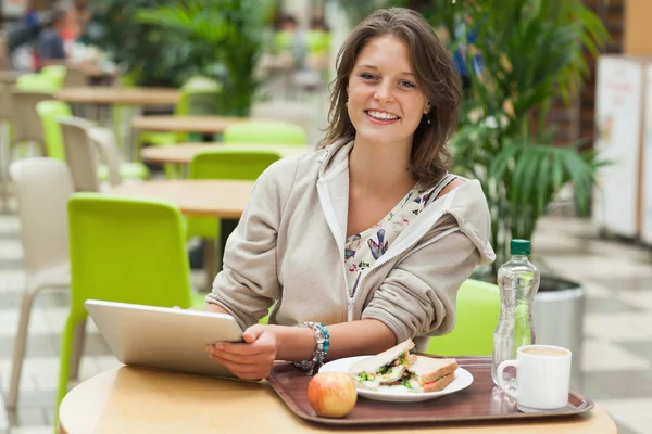 Vrouw met tablet pc en maaltijd in de cafetaria — Stockfoto
