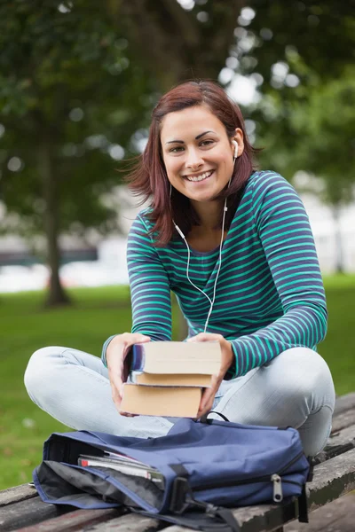 Веселый случайный студент, сидящий на скамейке с книгами — стоковое фото