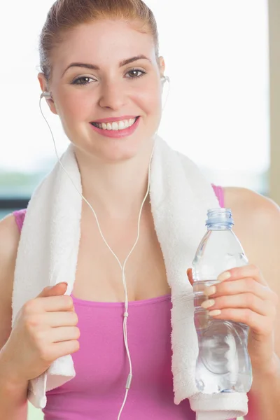 Mujer con toalla alrededor del cuello sosteniendo botella de agua en stu fitness — Foto de Stock