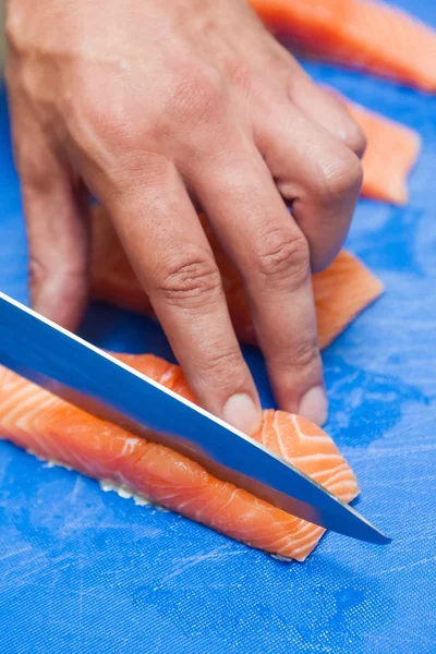 Close up of hand slicing salmon with sharp knife — Stock Photo, Image