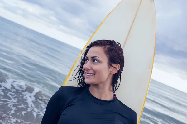 ビーチでサーフボードを抱えて離れて見て美しい女性 — ストック写真