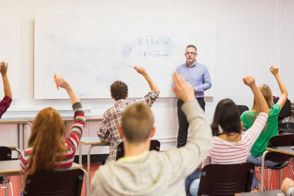 Estudantes levantando as mãos na sala de aula — Fotografia de Stock
