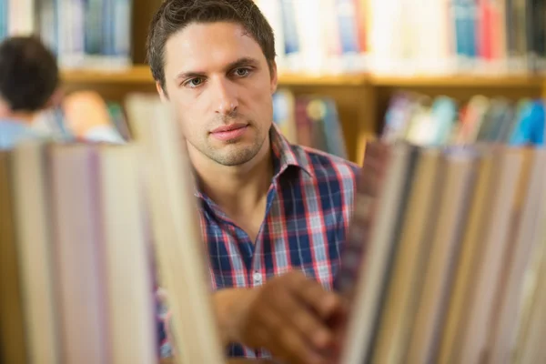 Mature student selecting book from shelf in library — Stock Photo, Image