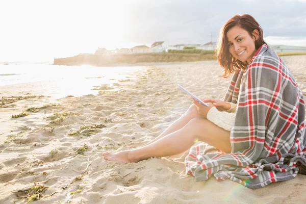 Vrouw bedekt met deken gebruiken, tablet pc op strand — Stockfoto