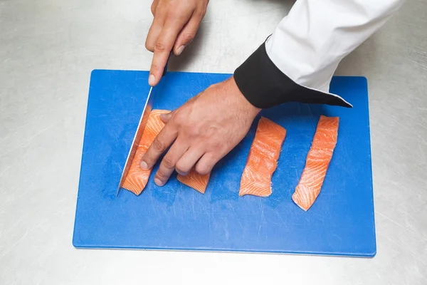 Chef slicing raw salmon with sharp knife — Stock Photo, Image