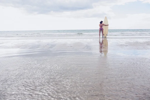 Mulher calma de biquíni com prancha de surf na praia — Fotografia de Stock