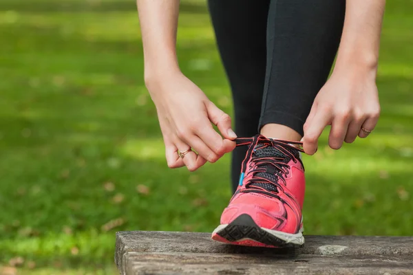 Mujer joven atando los cordones de sus zapatillas —  Fotos de Stock