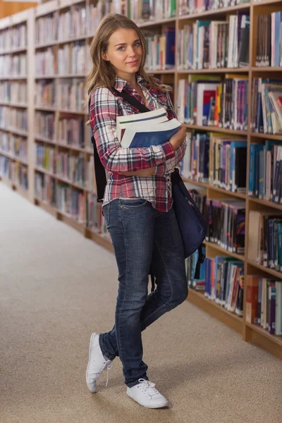 Hübsch lächelnde Studentin blickt in die Kamera, die Bücher hält — Stockfoto