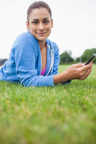 Ładna kobieta z telefonów komórkowych, leżąc na trawie — Zdjęcie stockowe