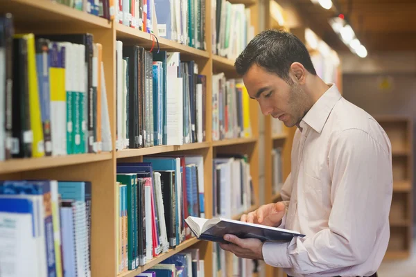 Intellektueller liest ein Buch, das in der Bibliothek steht — Stockfoto