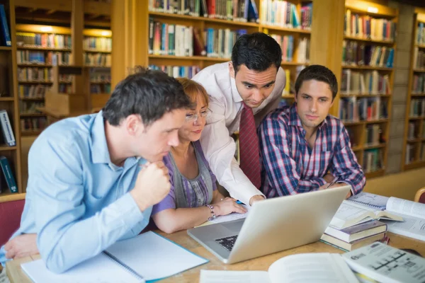 Volwassen studenten met de leraar en laptop in bibliotheek — Stockfoto