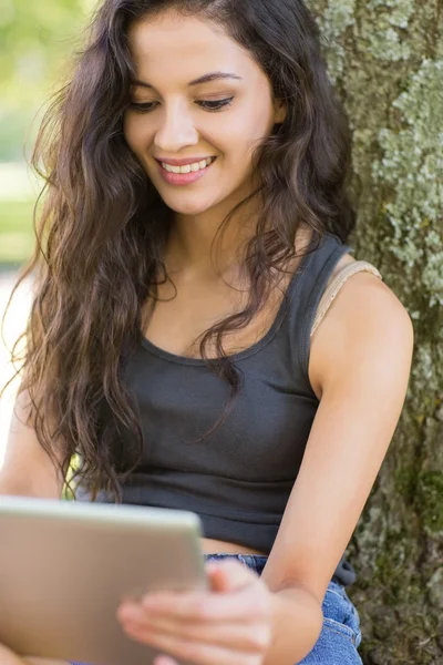 Casual cheerful brunette sitting using tablet — Stock Photo, Image