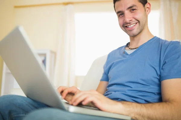 Człowiek siedzi na kanapie przy użyciu laptopa — Zdjęcie stockowe