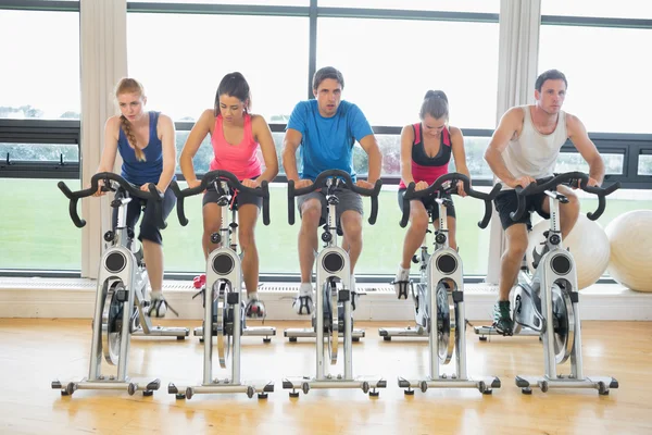 Personas decididas haciendo ejercicio en la clase de spinning en el gimnasio — Foto de Stock