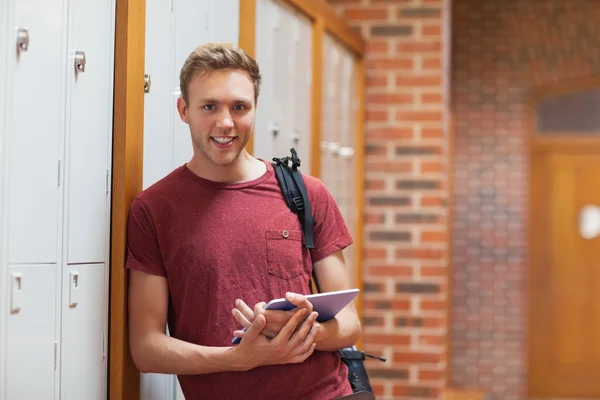 Knappe lachende student leunend tegen kluisjes met behulp van Tablet PC — Stockfoto
