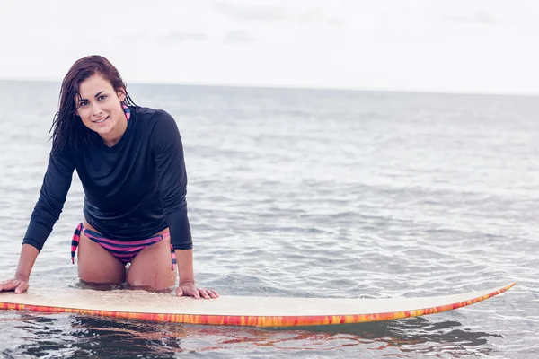 Schöne junge Frau mit Surfbrett im Wasser — Stockfoto