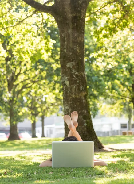 Brünette im Gras liegend mit ihrem Laptop — Stockfoto