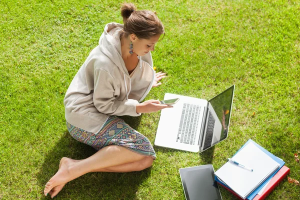 Student met behulp van mobiele telefoon laptop met boeken in het park — Stockfoto