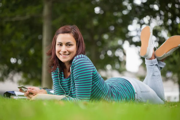 Lächelnder lässiger Student im Gras liegend und in die Kamera blickend — Stockfoto