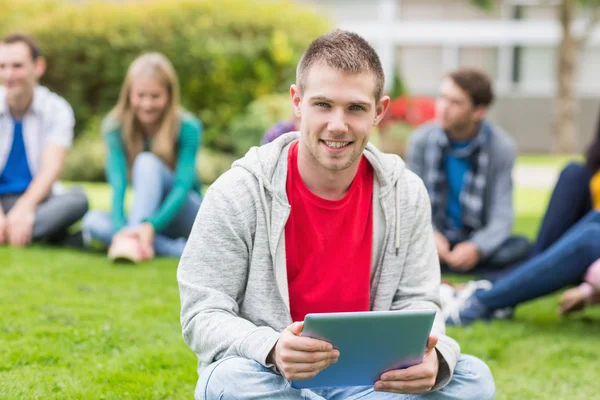 Sorrindo menino da faculdade segurando tablet PC com os alunos no parque — Fotografia de Stock