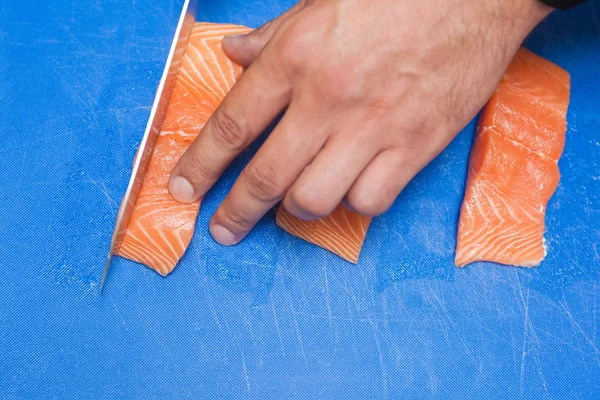 Close up of hand slicing raw salmon with sharp knife — Stock Photo, Image