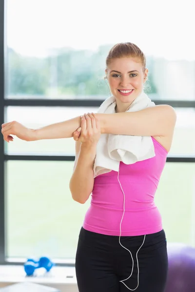 Vrouw met een handdoek om nek uitrekken hand in de fitness-studio — Stockfoto