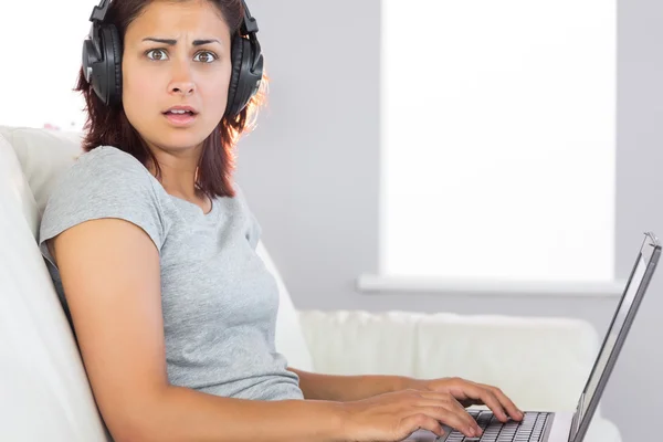 Mulher surpresa trabalhando com seu caderno e ouvindo música — Fotografia de Stock