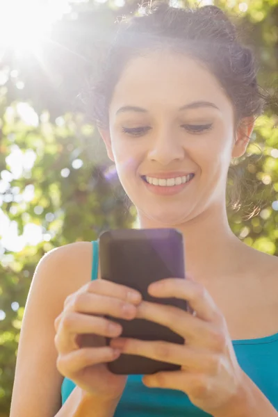 Mujer joven contenta marcando con su teléfono inteligente — Foto de Stock